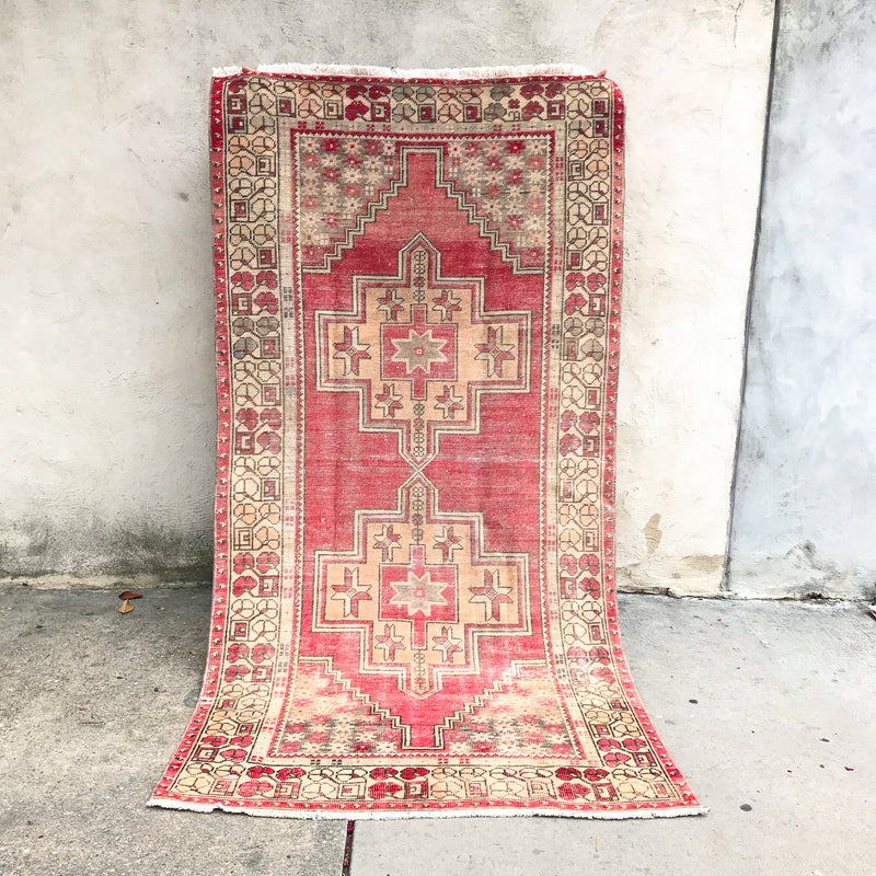 This handwoven vintage Turkish rug has beautiful neutral and light gold accents. Background color is a deep salmon pink / red. Niğde. 
