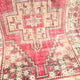 This handwoven vintage Turkish rug has beautiful neutral and light gold accents. Background color is a deep salmon pink / red. Niğde. 