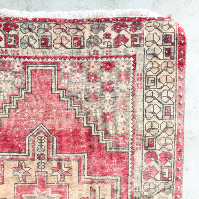 This handwoven vintage Turkish rug has beautiful neutral and light gold accents. Background color is a deep salmon pink / red. Niğde. 