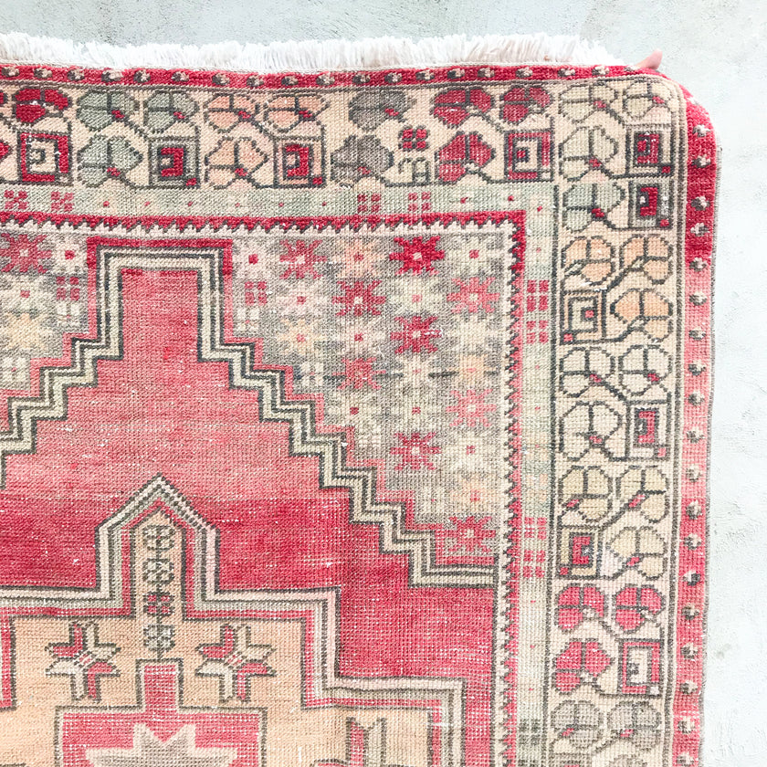 This handwoven vintage Turkish rug has beautiful neutral and light gold accents. Background color is a deep salmon pink / red. Niğde. 