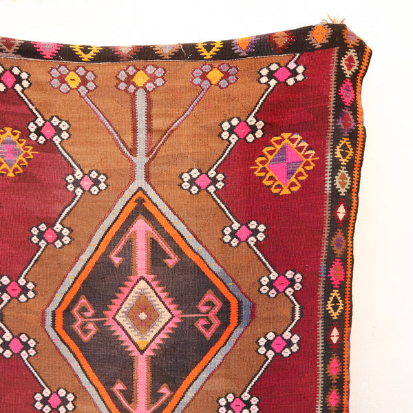 This large vintage Kars Turkish kilim has a beautiful field of a light burgundy with camel, pink, and yellow accents. 